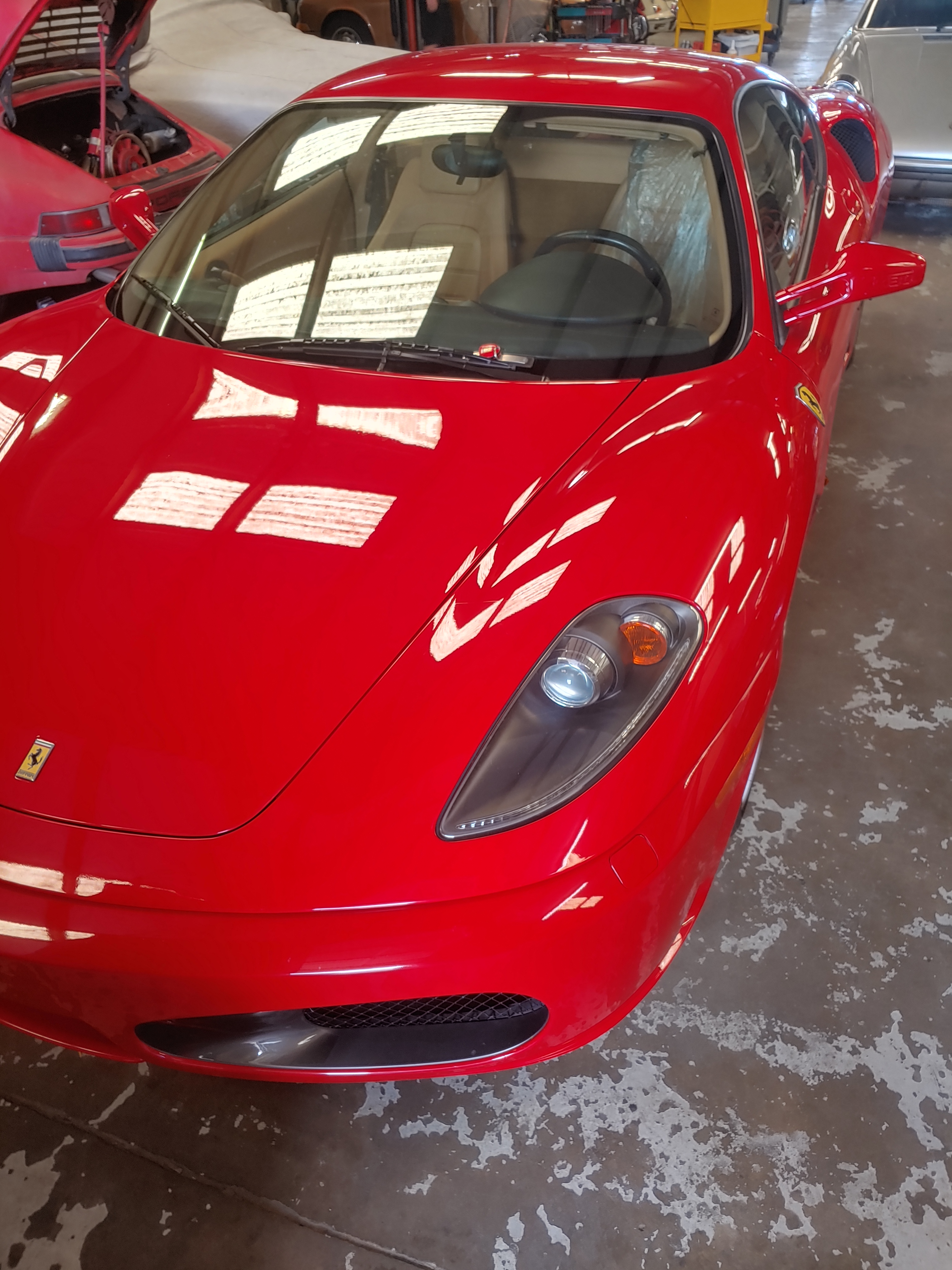 A red Ferrari sports car is parked in a garage, with the front of the vehicle prominently displayed. The car's sleek desig...