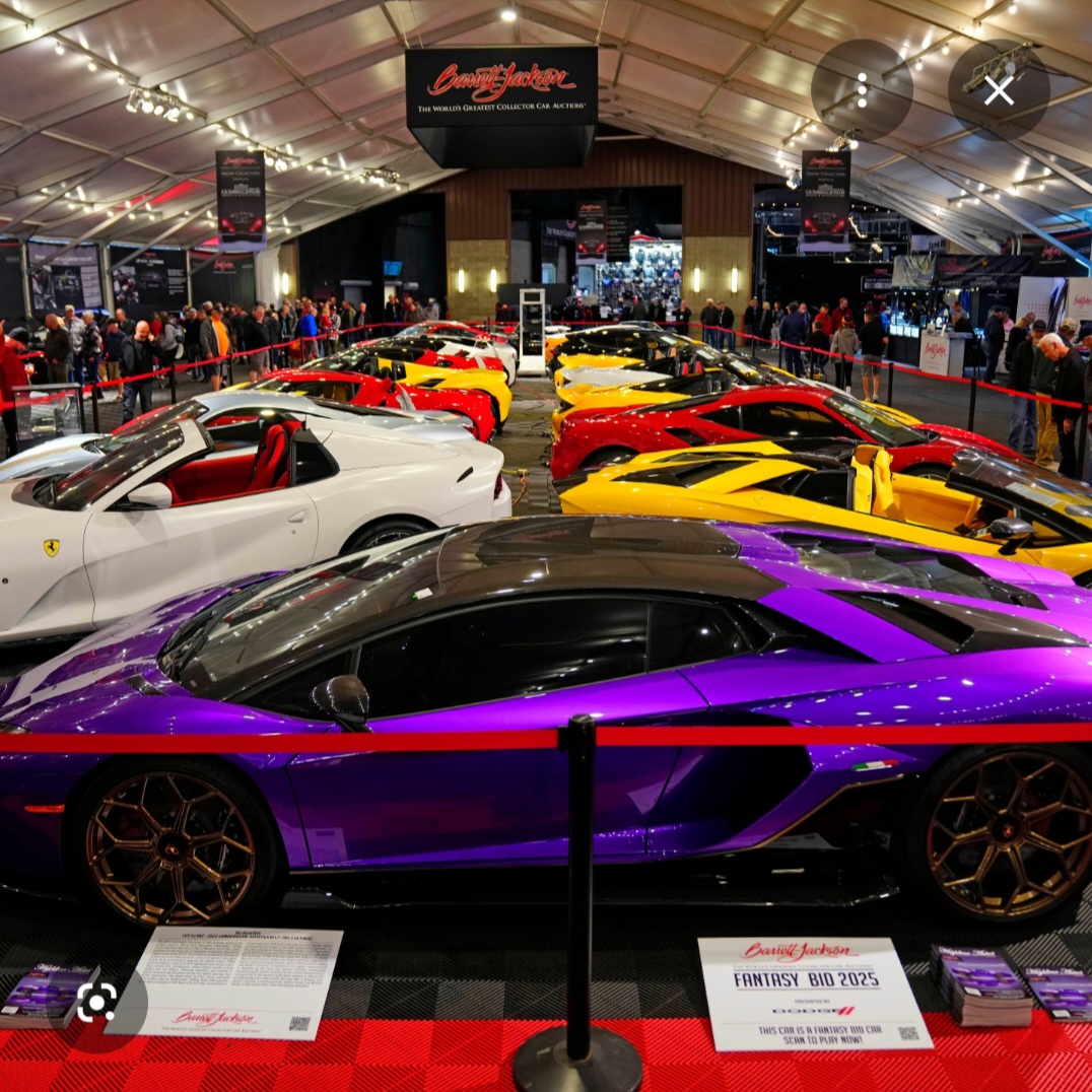 The image depicts a large room filled with numerous sports cars, likely at an auction or exhibition. The cars are arranged...
